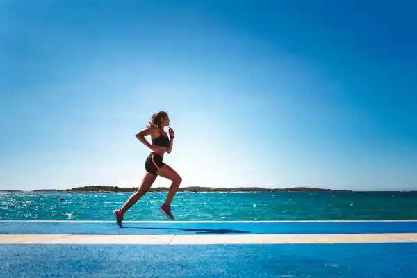 Woman running showing strong leg muscle Pinner